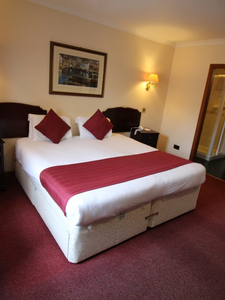 A comfortable bed in a hotel room, conveniently located near the popular Elgin restaurant and bar.