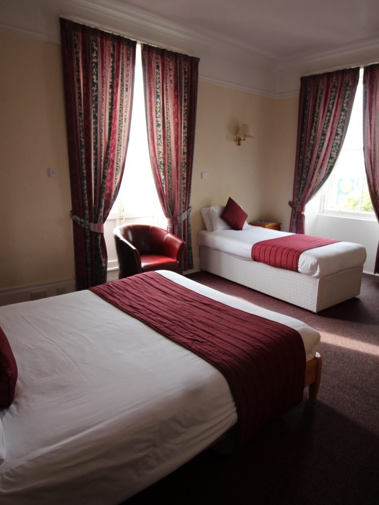 Two beds in a room overlooking a window.